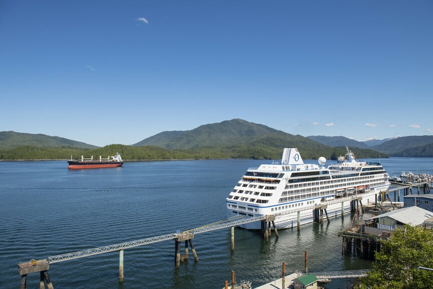 Prince Rupert with large cruise ship docked in the marina, cargo ship on the ocean in distance.