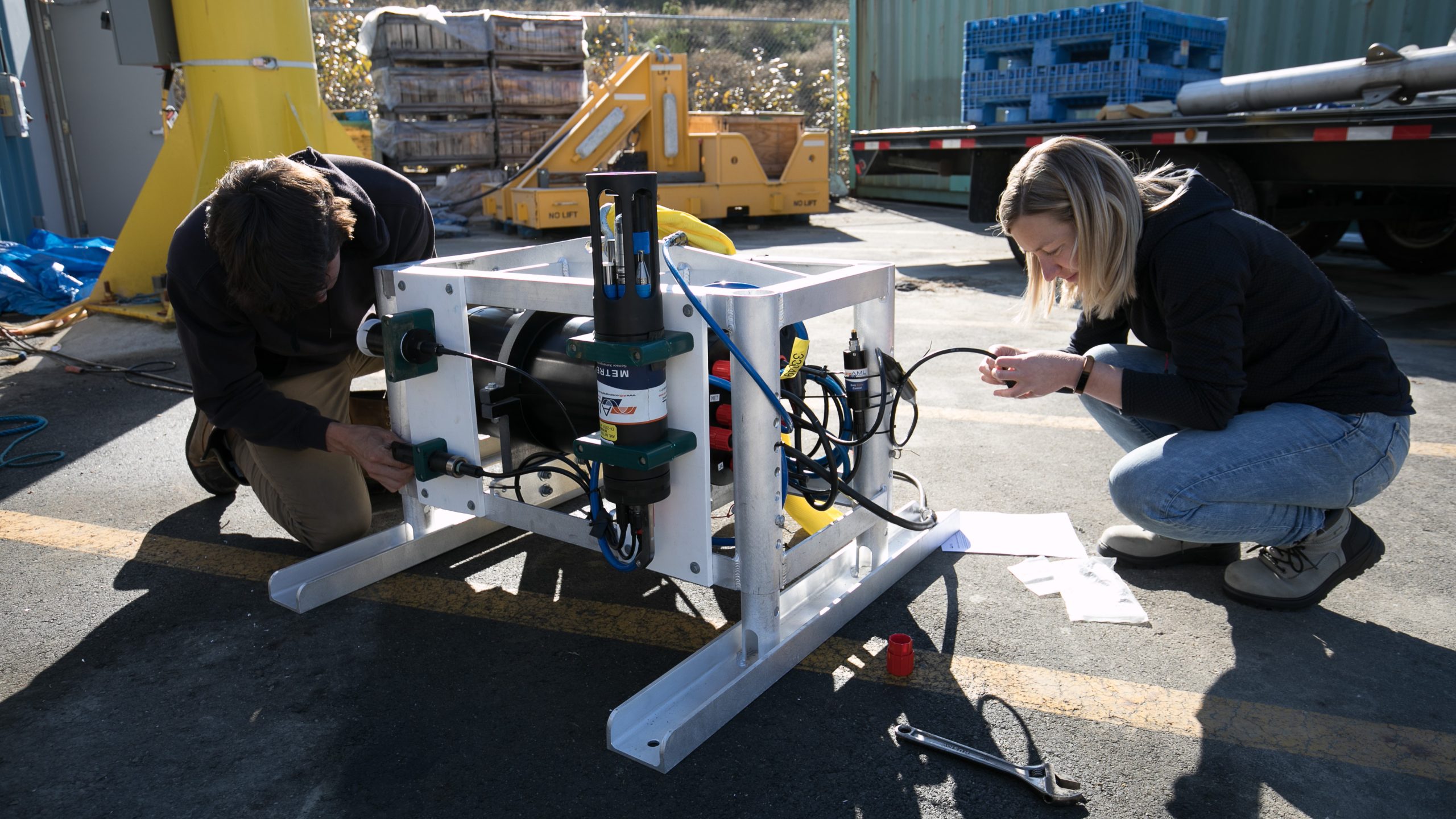 Two people working on a robot for marine technology.