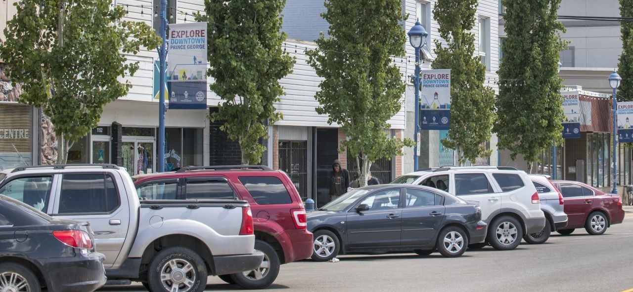 Downtown street view of Prince George. Stores and cars parked.